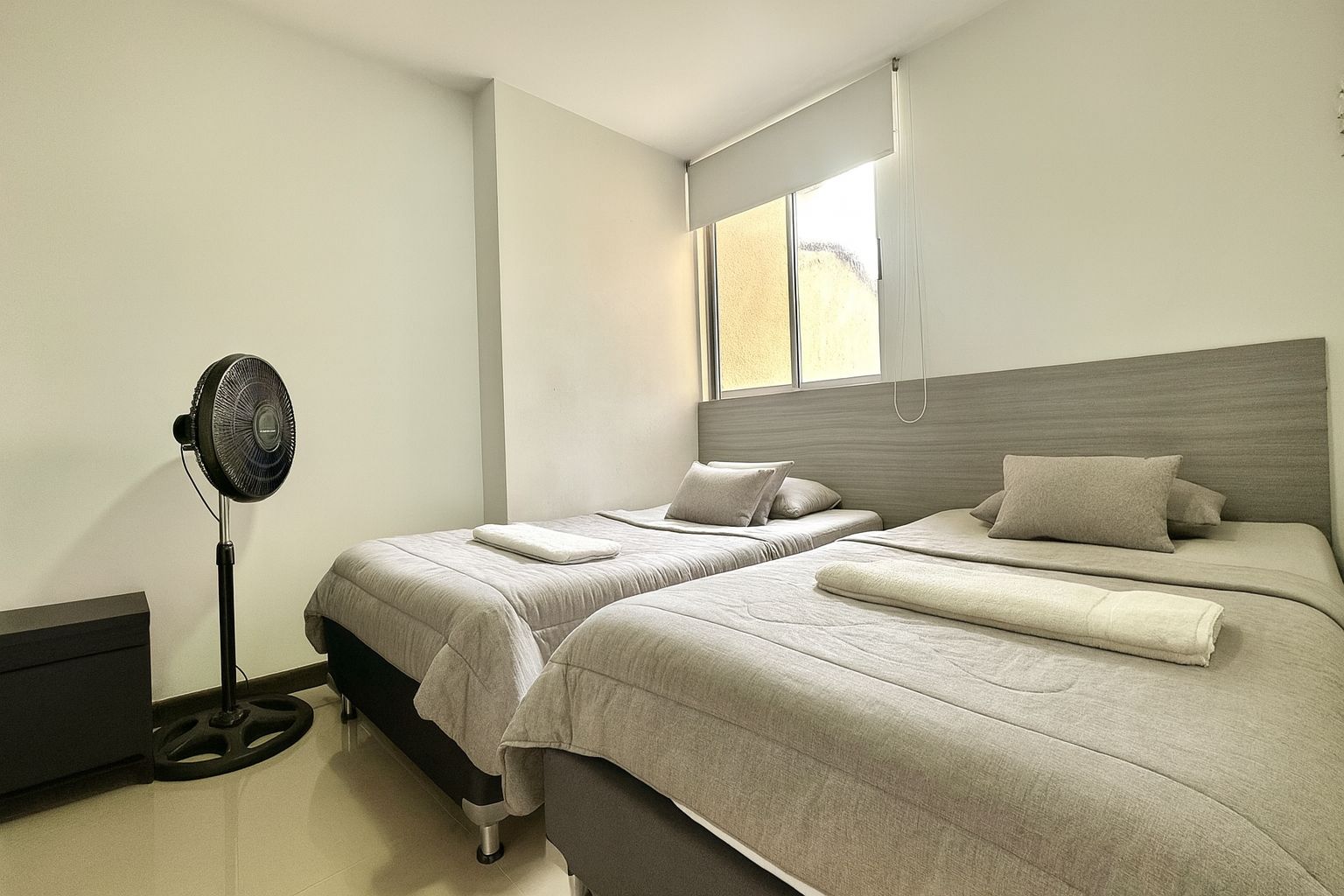 Un dormitorio con dos camas, un ventilador y una ventana.