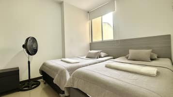 Un dormitorio con dos camas, un ventilador y una ventana.
