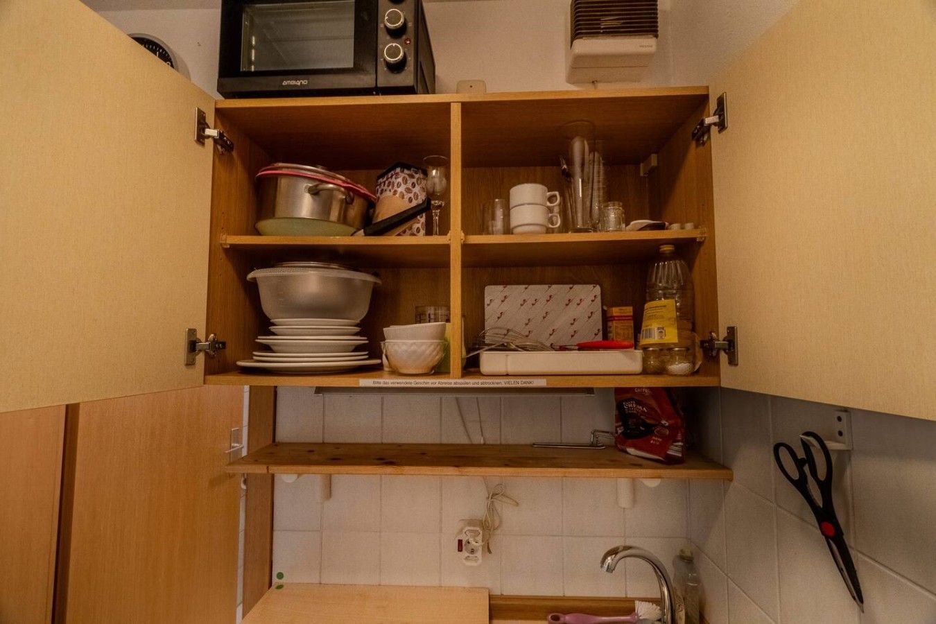 Eine Küche mit Holzschränken, einer Mikrowelle, einem Spülbecken und diversen Küchenutensilien.