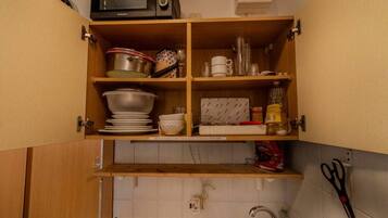 Eine Küche mit Holzschränken, einer Mikrowelle, einem Spülbecken und diversen Küchenutensilien.