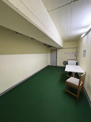 Een kamer met een groen tapijt, een witte tafel en een houten stoel.