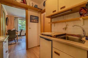 Een kleine keuken met een spoelbak, aanrecht en houten kastjes.