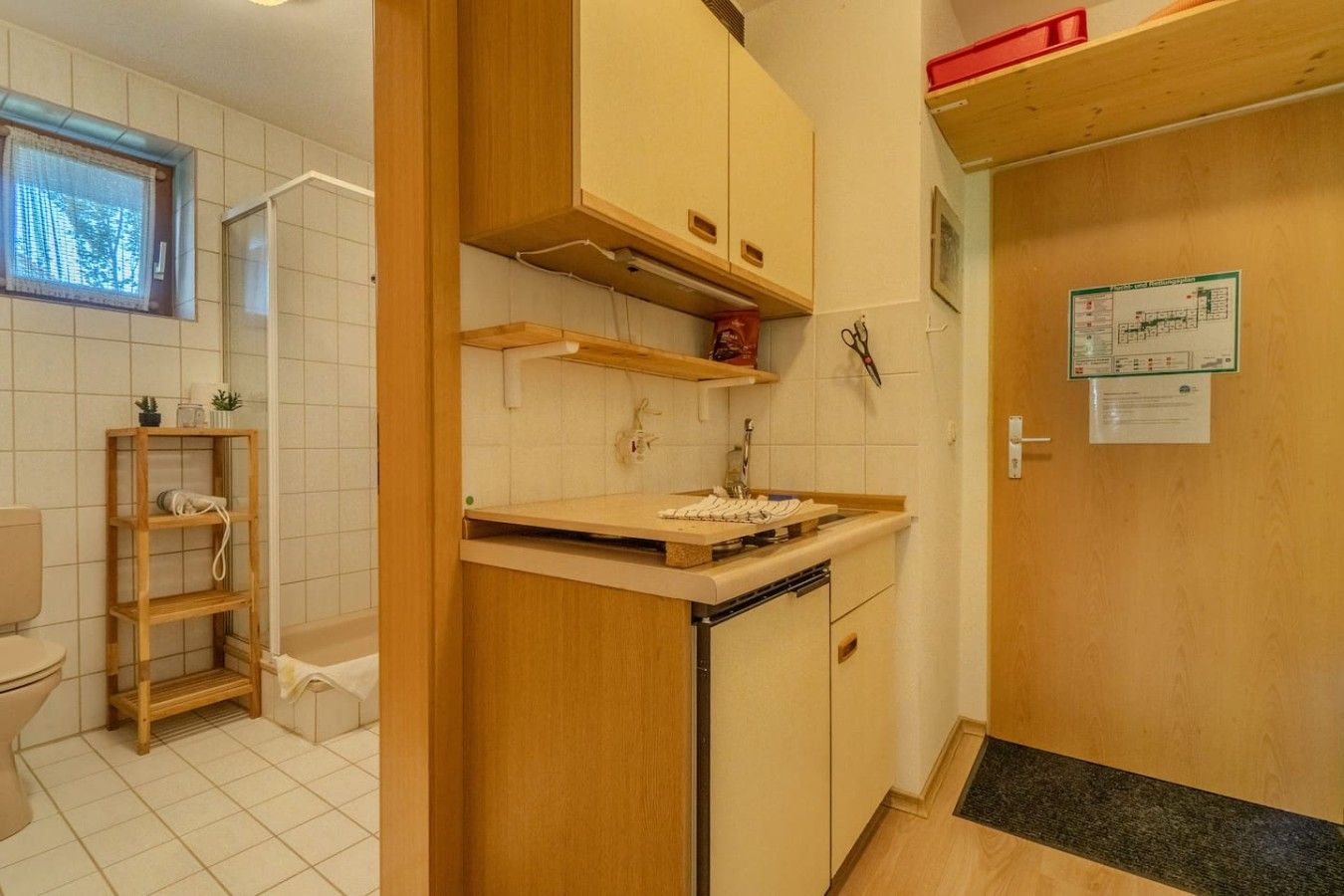 A compact kitchen with wooden cabinets, a built-in dishwasher, and a small countertop.