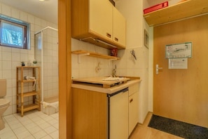 Een praktische keuken met houten kastjes, een inbouwvaatwasser en een klein aanrecht.
