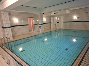 An indoor swimming pool with tiled walls, a tiled floor, and a visible door leading to another room. - Idyllic 1-bedroom apartment, sauna, national park, parking (Zwiesel)