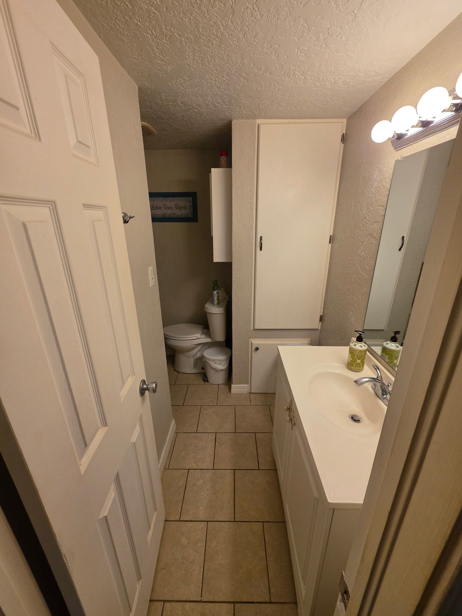 A compact bathroom with a toilet, sink, and mirror.