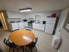A compact kitchen with white cabinets, a microwave, a stove, and a refrigerator. - The Hidden Gem: Cozy Blue Cottage Sleeps 6, 10 min. to OU . Pet friendly (Noble)