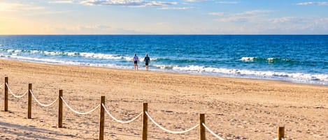 Una playa arenosa con una cerca de madera y una barrera de cuerda.