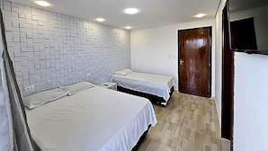 Habitació d'hotel amb dos llits, una paret de rajola, una porta de fusta i un televisor.