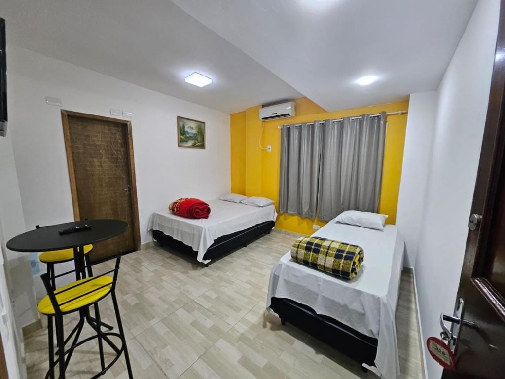 Une chambre de taille modeste, avec deux lits, une petite table et une chaise.