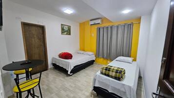 Une chambre de taille modeste, avec deux lits, une petite table et une chaise.