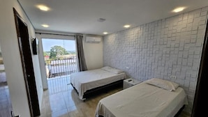 Habitació d'hotel amb dos llits, un balcó i una paret amb rajoles.