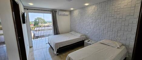 Habitación de hotel con dos camas, un balcón y una pared con azulejos.