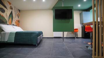 Ein Schlafzimmer mit einem Bett, einem grünen Wandfernseher und einem roten Sessel.