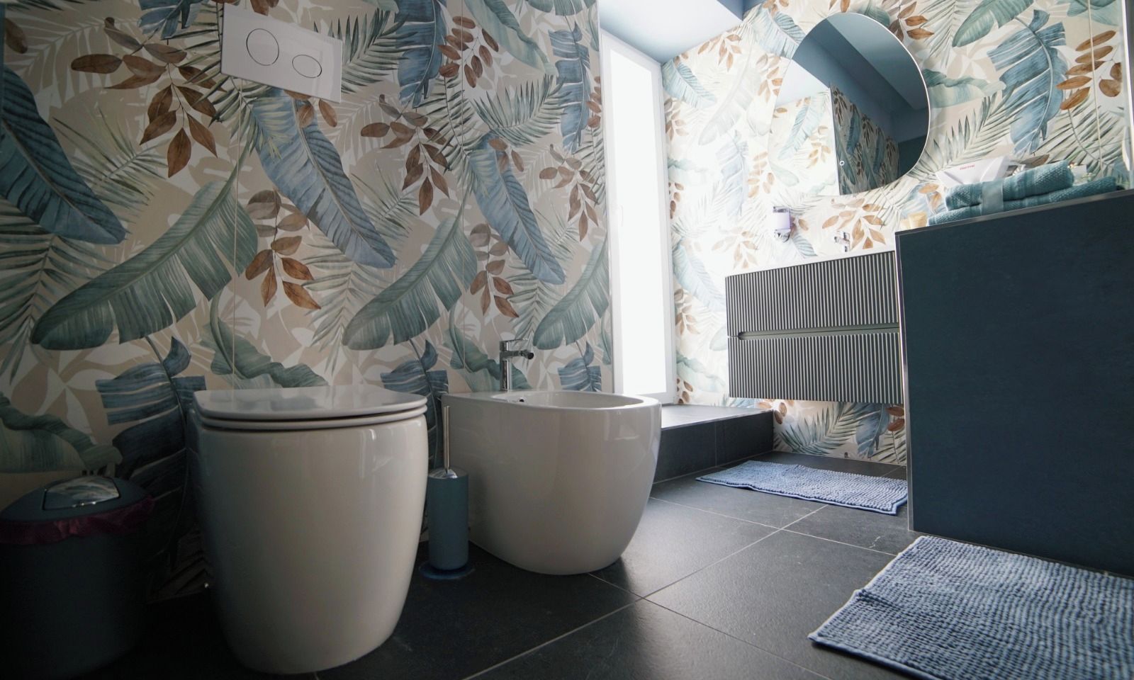 A bathroom with two toilets, a sink, and a mirror.