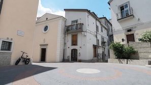 Une cour avec une zone circulaire pavée, un bâtiment doté d’un balcon et un vélo garé.