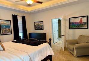 A bedroom with a bed, a chair, and two framed pictures on the wall.