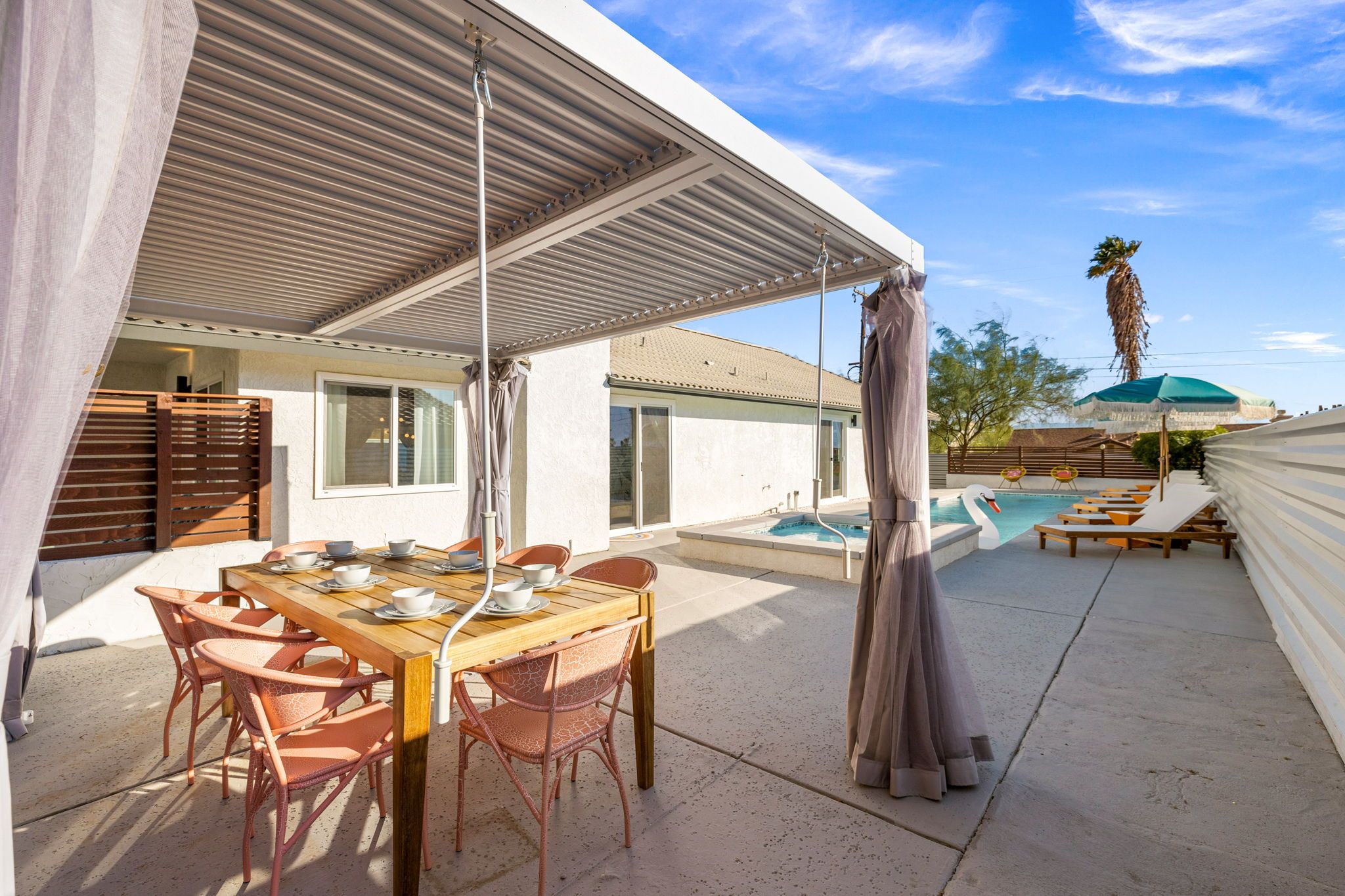 Un espace extérieur abrité, aménagé pour les repas, avec une piscine et des chaises longues.