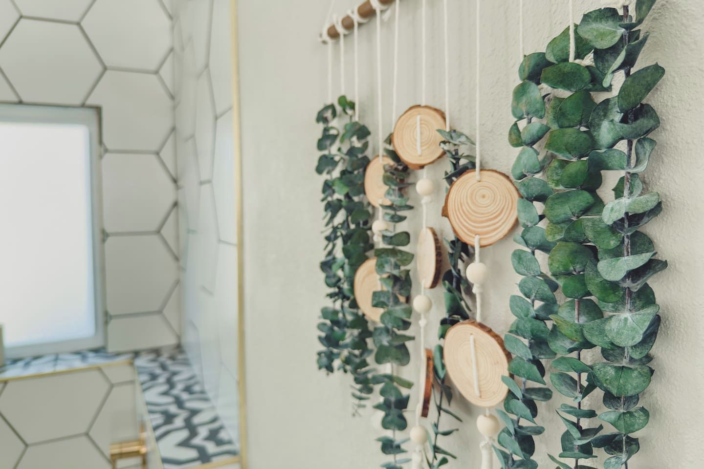 Un mur orné d’une décoration suspendue composée de tranches de bois et de feuillage vert.