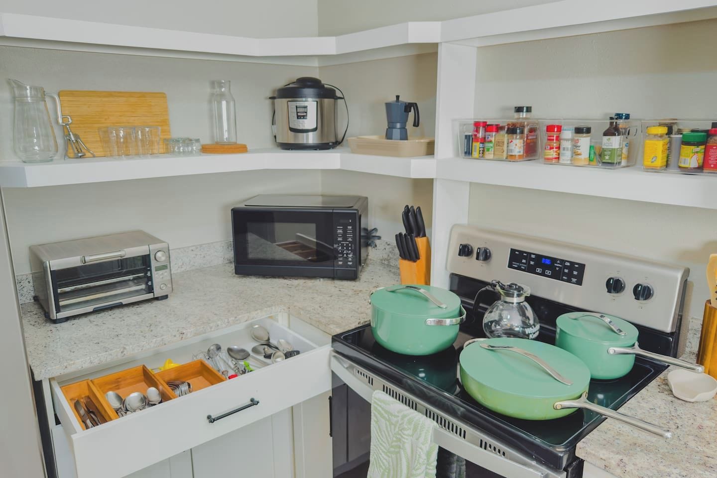 A kitchen with a toaster, microwave, stove, and various utensils.