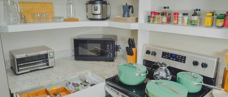 A kitchen with a toaster, microwave, stove, and various utensils.