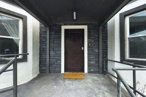 A building entrance with a dark wooden door, stone walls, and a concrete floor. - Travelers Dream - 2 Homes 1 Stay (Colorado Springs)