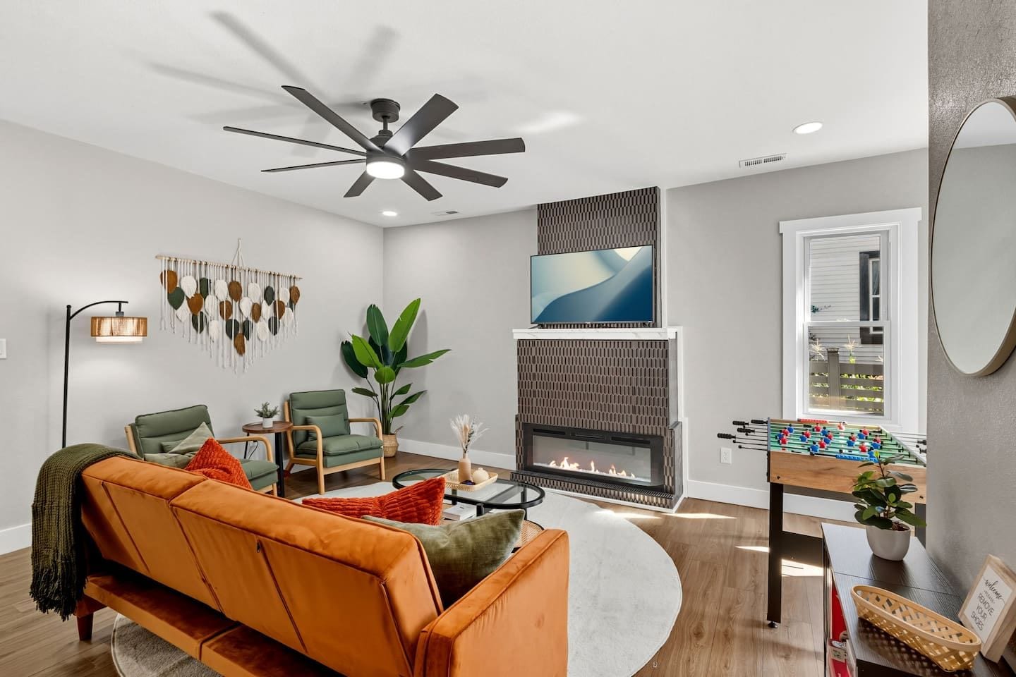 A modern living room with a fireplace, seating area, and a foosball table.