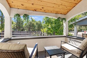 An outdoor patio with wicker furniture, a table, and hanging plants. - Travelers Dream - 2 Homes 1 Stay (Colorado Springs)