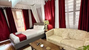 A hotel room with a bed, a sofa, a coffee table, and a potted plant.