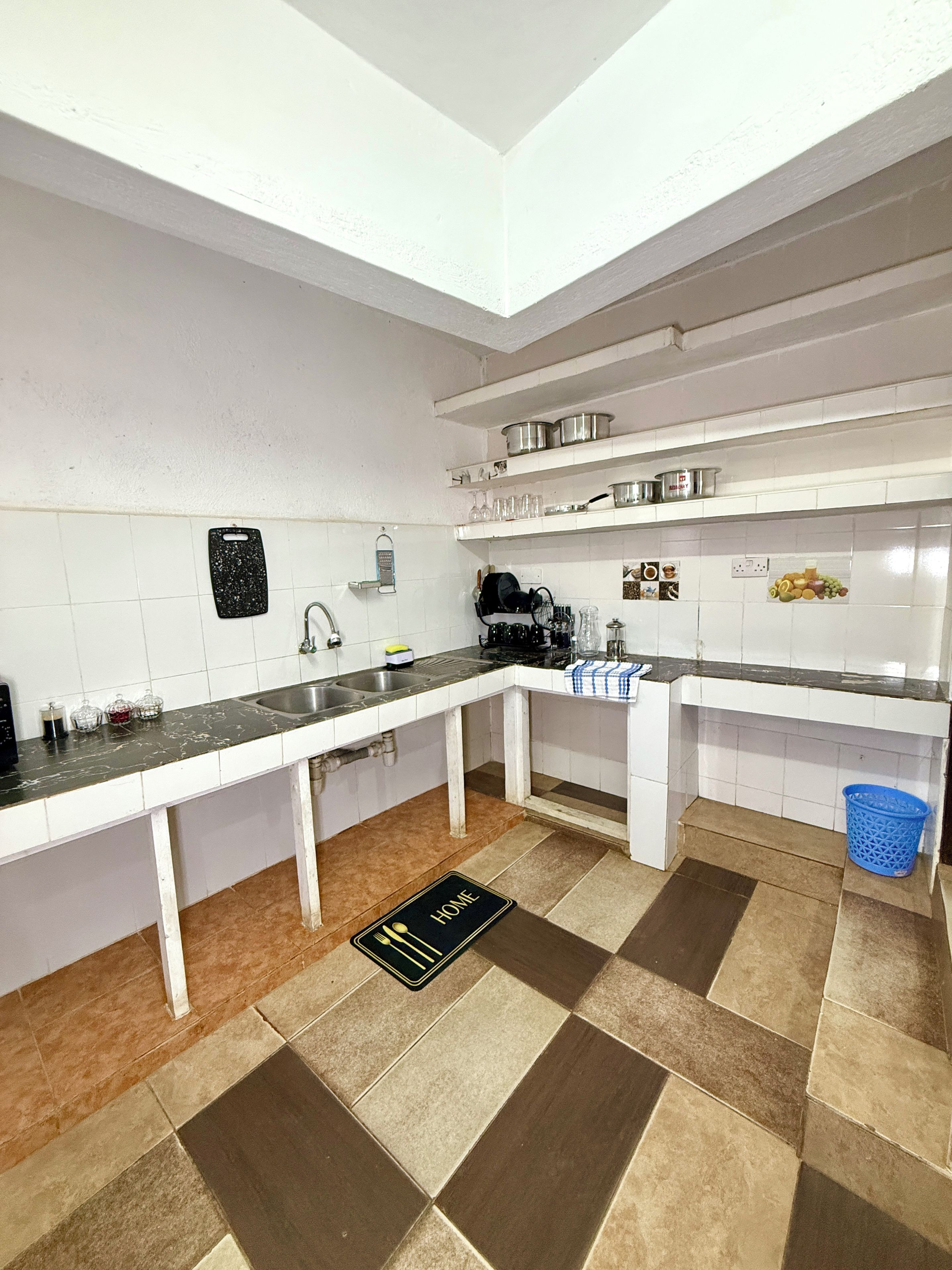 Una cocina con una encimera larga, un lavabo y una cesta azul.