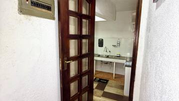 A hallway with a wooden door leading to a kitchen area.