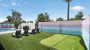 A backyard with a pool, lawn chairs, a putting green, and a colorful wall. - Private Pool & put put Oasis with a Great location (Scottsdale)