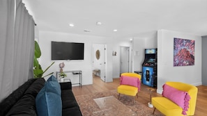 A modern living room with a black sofa, two yellow armchairs, a flat-screen TV, and a gaming console. - Private Pool & put put Oasis with a Great location (Scottsdale)