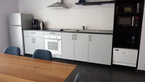 Cozinha moderna com armários brancos, forno embutido, máquina de café e micro-ondas.