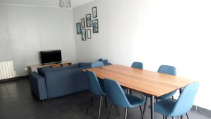 Uma sala de estar moderna com um sofá seccional, uma mesa de jantar de madeira e cadeiras azuis.