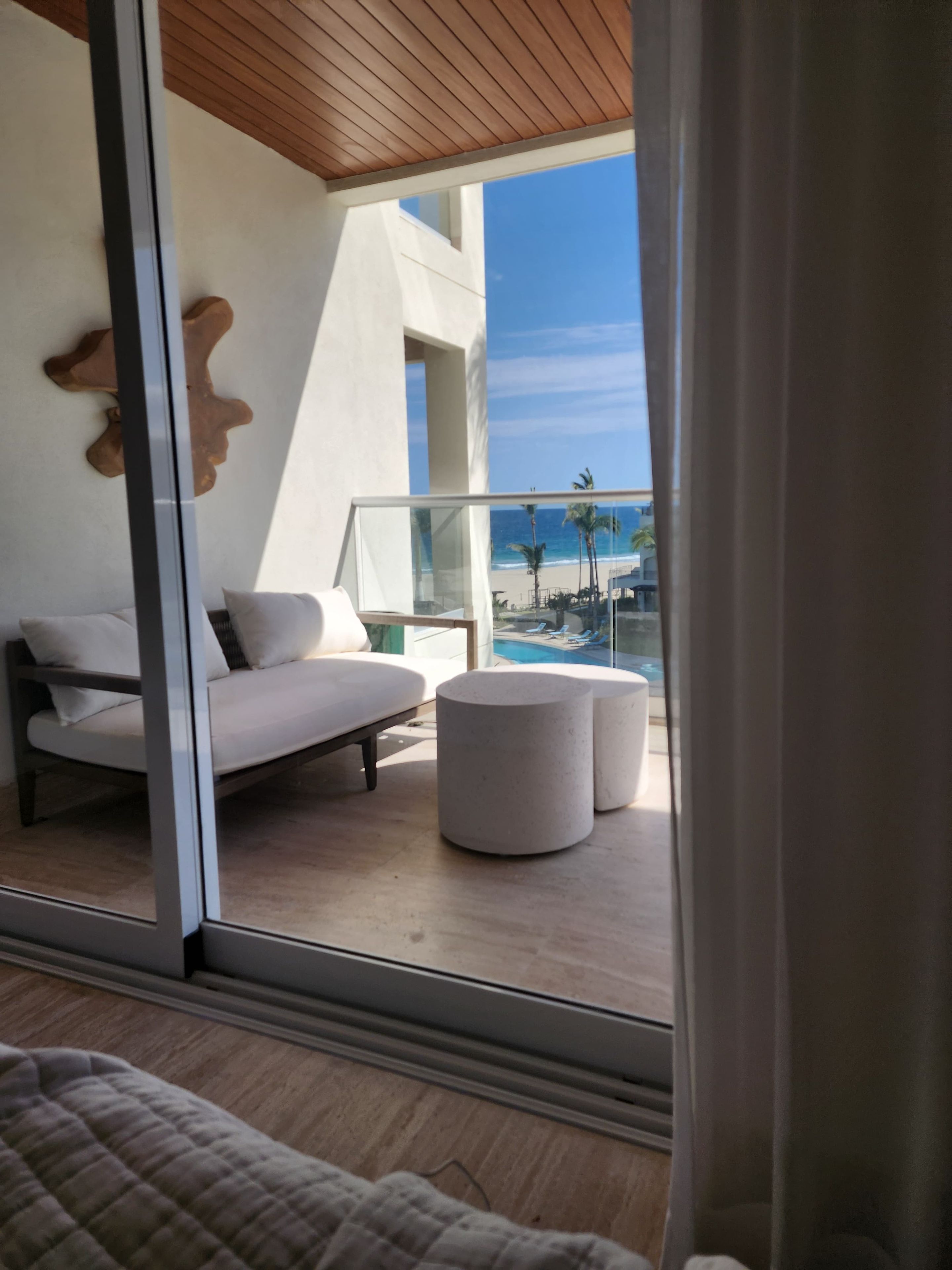 A modern room with a glass door leading to a balcony overlooking a beach.