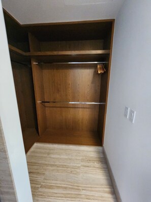 Ein begehbarer Kleiderschrank mit Holzregalen und einer Metallstange.