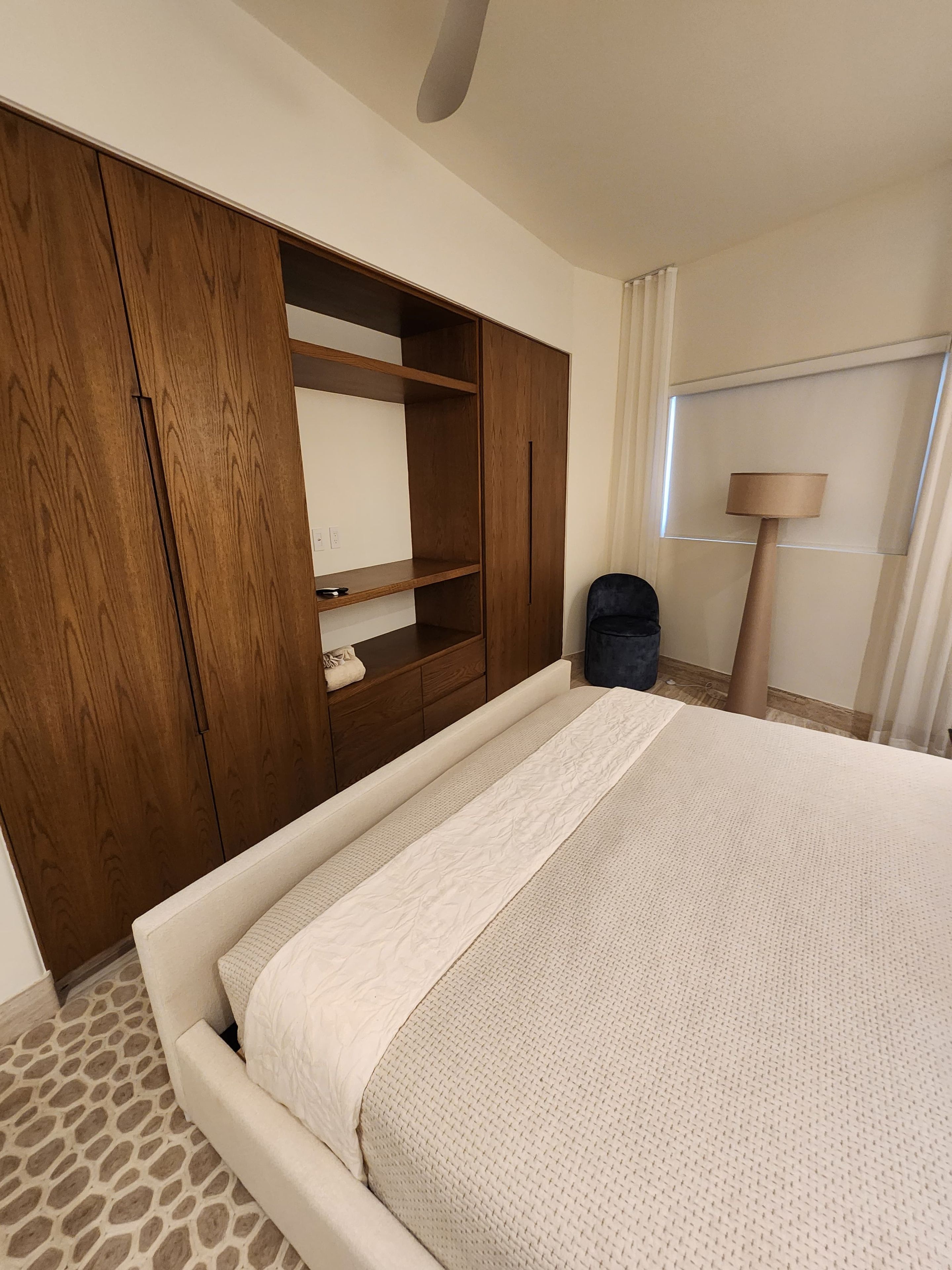 Un dormitorio con una cama grande, un armario de madera y una lámpara de noche.