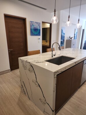 A modern kitchen with a marble countertop, a sink, and pendant lighting. - Oceanfront Luxury at Tortuga Bay · Infinity Pools hot tubs & 2 King Suites (San José del Cabo)