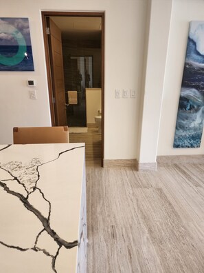 Une pièce avec un plancher en bois, une porte donnant sur une salle de bain et un tableau accroché au mur.