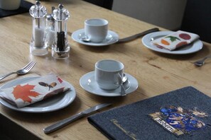 Mesa posta com pratos, copos, talheres e um cardápio.