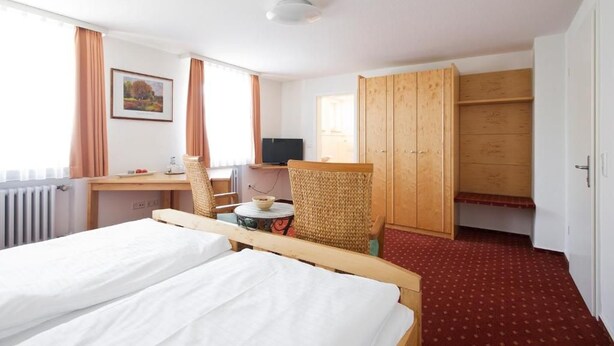 A hotel room with a bed, a desk with a chair, a television, and a wardrobe. - Landgasthof Lamm (Aalen-Ebnat)