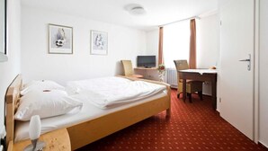A hotel room with a single bed, a desk, a chair, a television, and two framed pictures on the wall. - Landgasthof Lamm (Aalen-Ebnat)