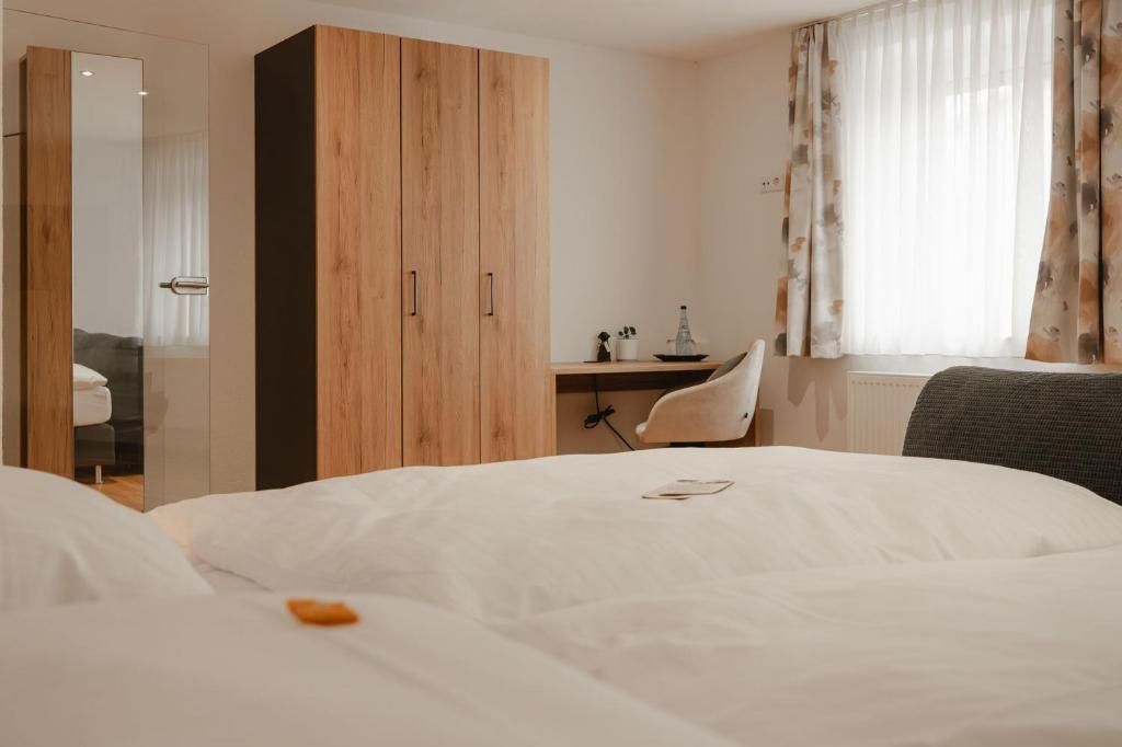 A hotel room with a bed, a desk, a chair, and a wardrobe.