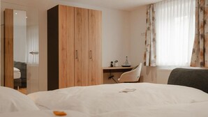 A hotel room with a bed, a desk, a chair, and a wardrobe. - Landgasthof Lamm (Aalen-Ebnat)