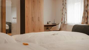 A hotel room with a bed, a desk, a chair, and a wardrobe.
