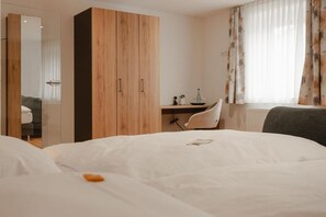 Una habitación de hotel con cama, escritorio, silla y armario.
