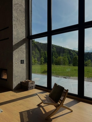 Una habitación con ventanas amplias, una chimenea y vistas a un paisaje boscoso.