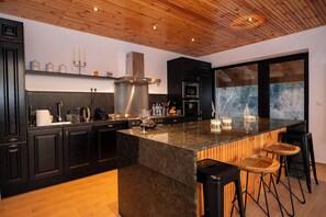 Una cocina moderna con armarios oscuros, una isla central grande y techo de madera.