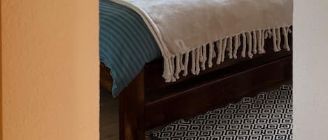 A bedroom with a bed, a nightstand, a lamp, and a mirror.